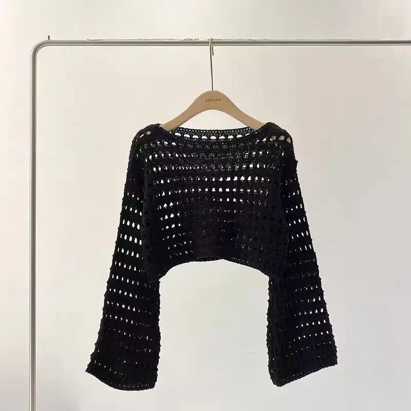 Black crochet sweater on a hanger against a white background