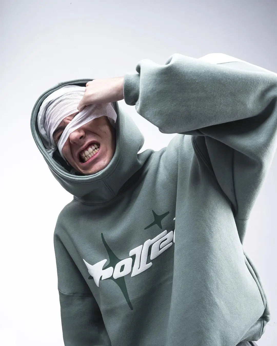 Person wearing a gray hoodie with a logo, pulling down the hood over their head.