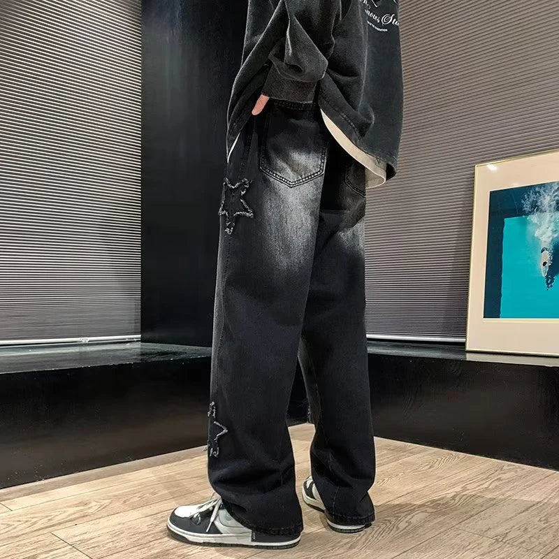 Person wearing black jeans with star designs in a room with a framed picture on the wall.