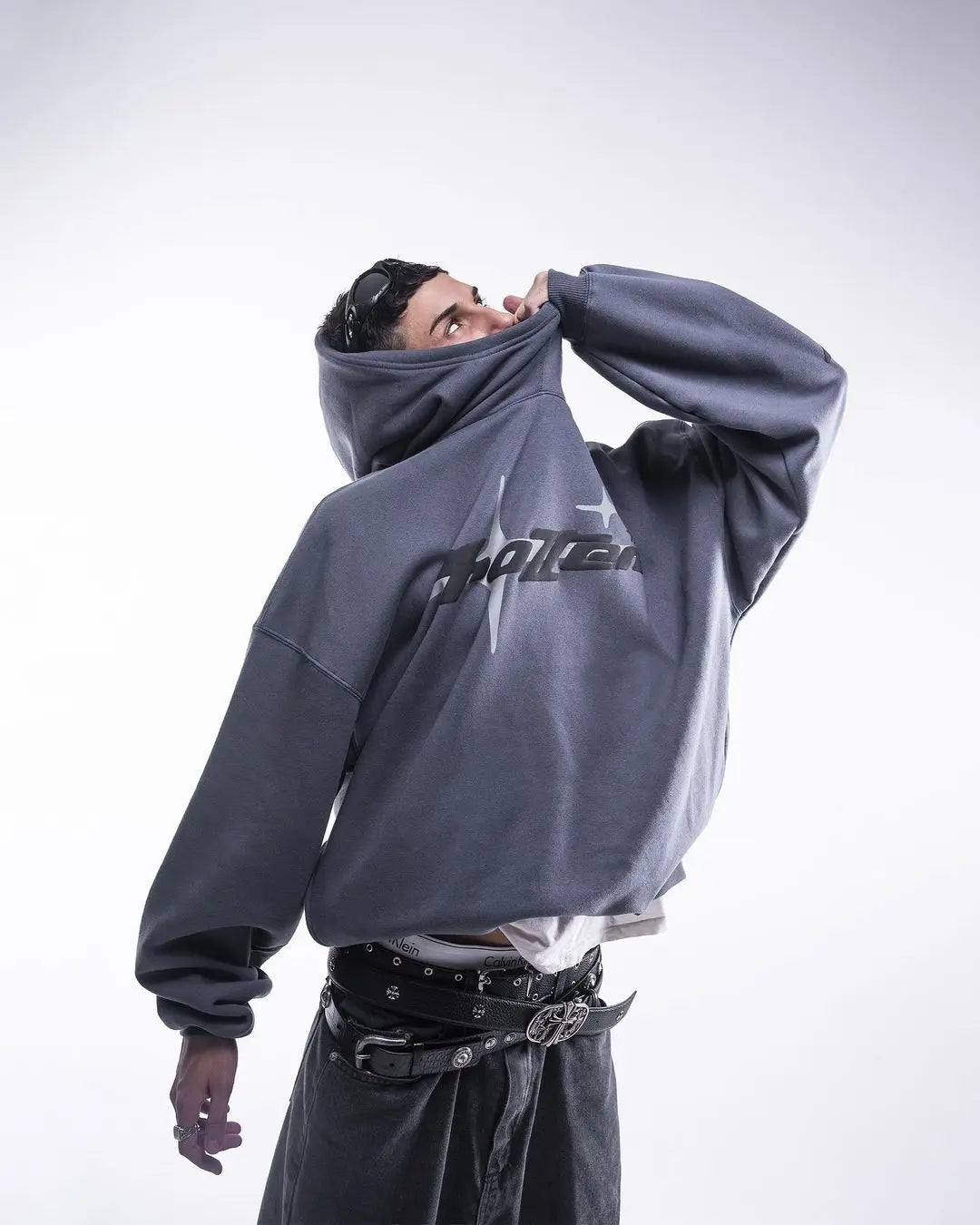 Person wearing a gray hoodie with a brand logo on a white background