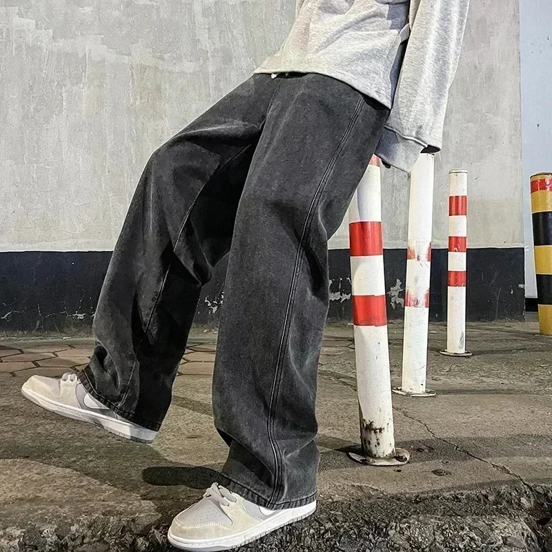Person wearing black jeans and white sneakers standing on a sidewalk with traffic poles in the background.